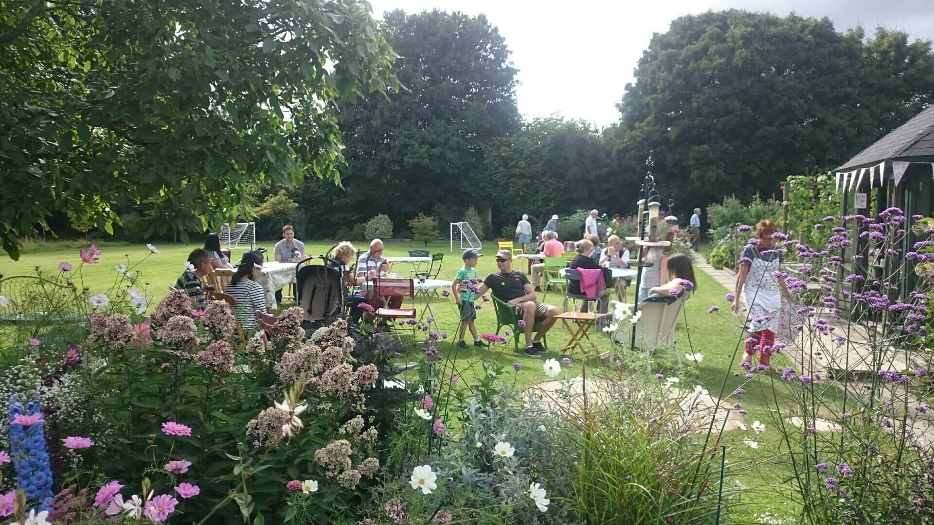 People drinking tea and eating cake on a sunny day in the nursery garden